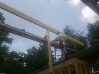 Carpenter setting a ridge beam over a new addition frame — Ice Dam Removal by Roofing Brothers in Galeton