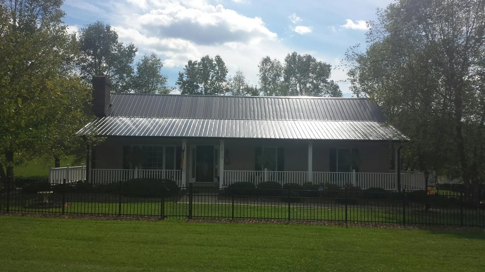 Gray metal roof on a brick ranch with a full width front porch — Gutter Guard Installation work by our crew in Galeton