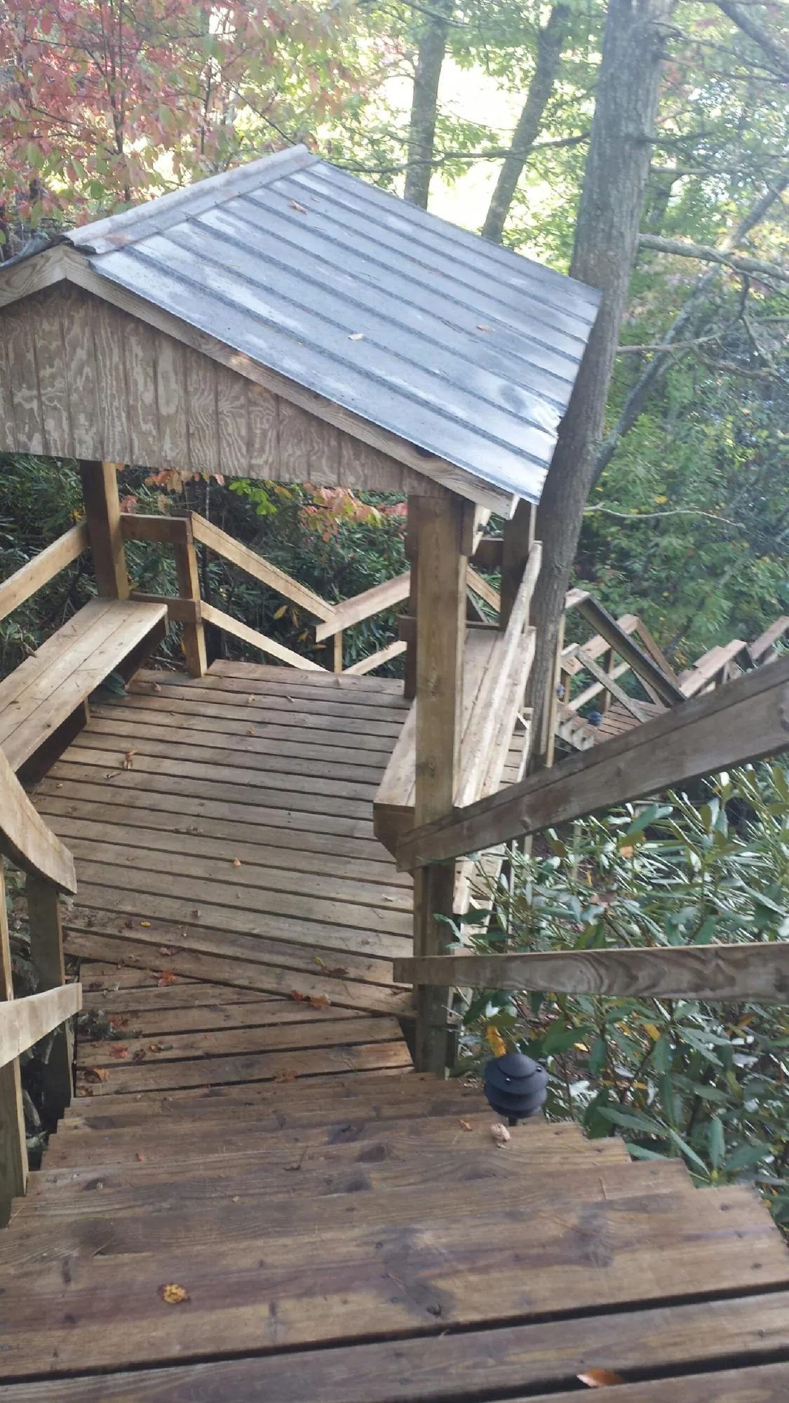 Metal roofed shelter over wooden steps on a wooded walkway — Skylight Repair & Installation work by our crew in Galeton