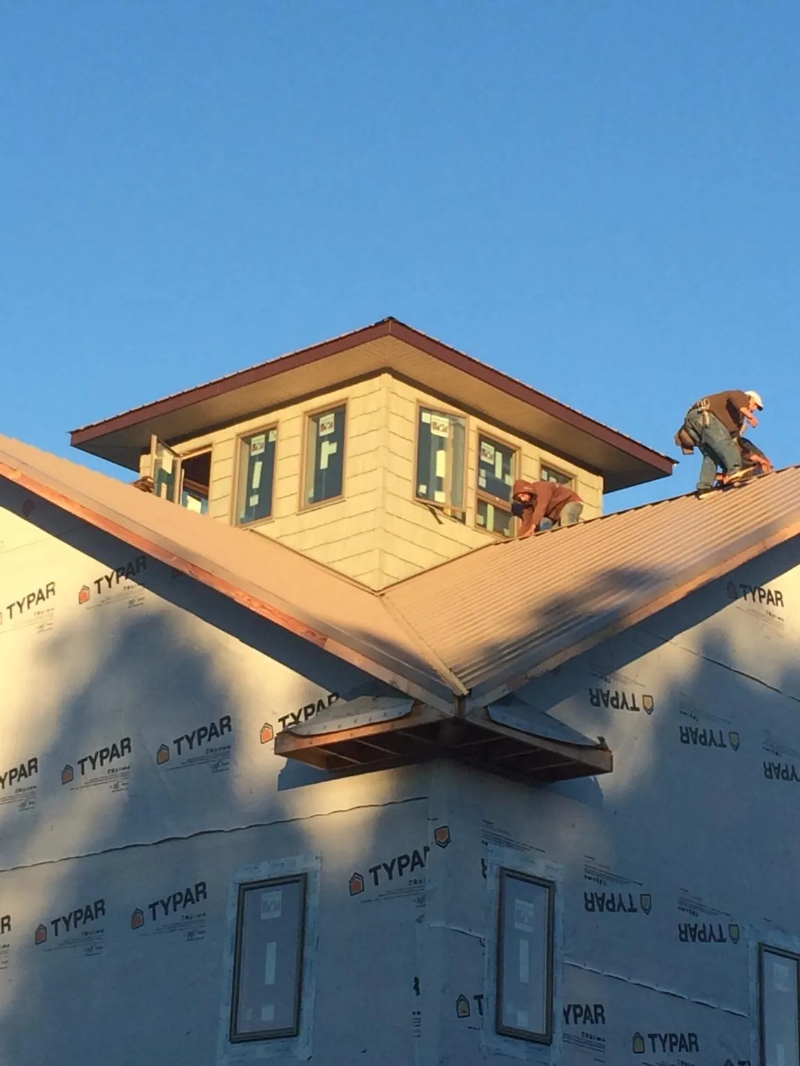 Roofers working around a rooftop cupola on a new metal roof at sunset — Roof Waterproofing in Galeton by Roofing Brothers